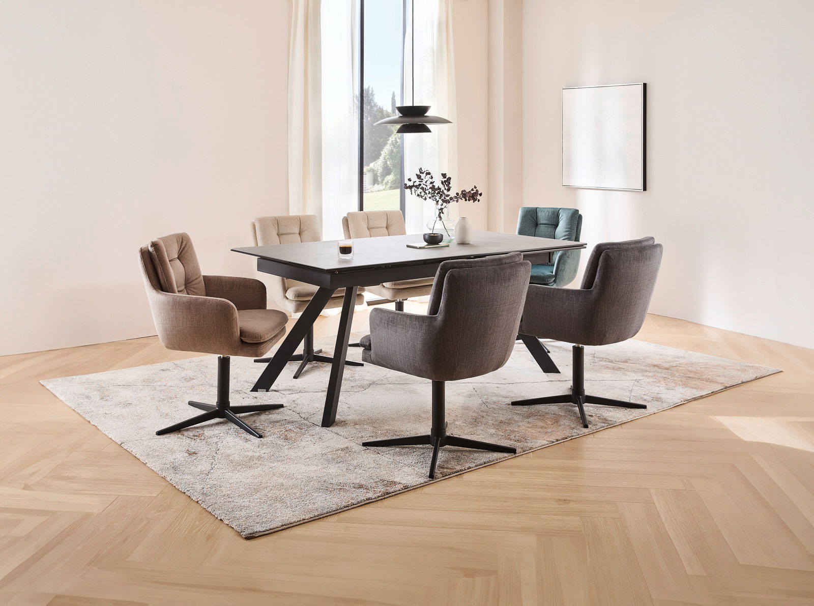 Novel Armlehnstuhl INGO Moderner Essbereich mit einem rechteckigen Esstisch und sechs gepolsterten Armlehnstühlen in verschiedenen Farben, auf einem Teppich in einem hellen Raum mit großen Fenstern. Perspektive von schräg oben.