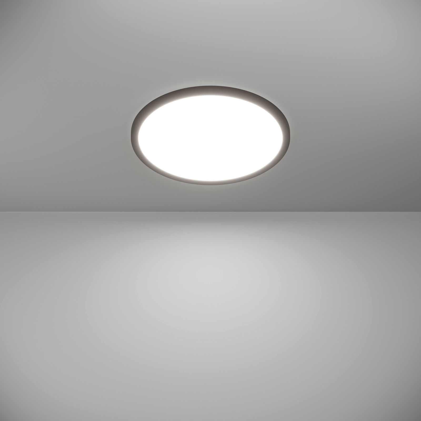 Runde LED-Deckenleuchte ROVITO-Z, Ansicht von unten, leuchtend an einer grauen Decke montiert.