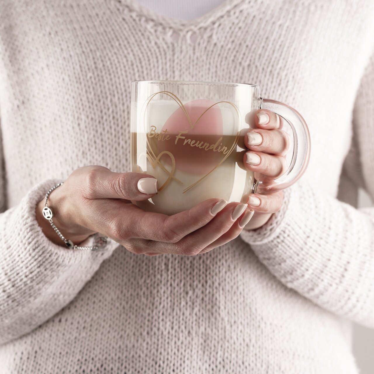Leonardo Geschenktasse Beste Freundin EMOZIONE Frau hält eine durchsichtige Tasse mit der Aufschrift 'Beste Freundin' und Herzmotiv, gefüllt mit Kaffee, aus der Vorderansicht.