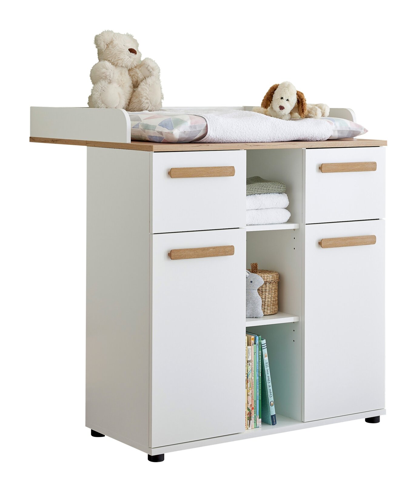 Wickelkommode in Weiß mit Holzauflage, vier Schubladen und offenen Regalfächern, oben Wickelauflage mit Handtuch und zwei Kuscheltieren, freigestellt vor weißem Hintergrund, Perspektive: frontale Ansicht mit leichter Seitenansicht von links.