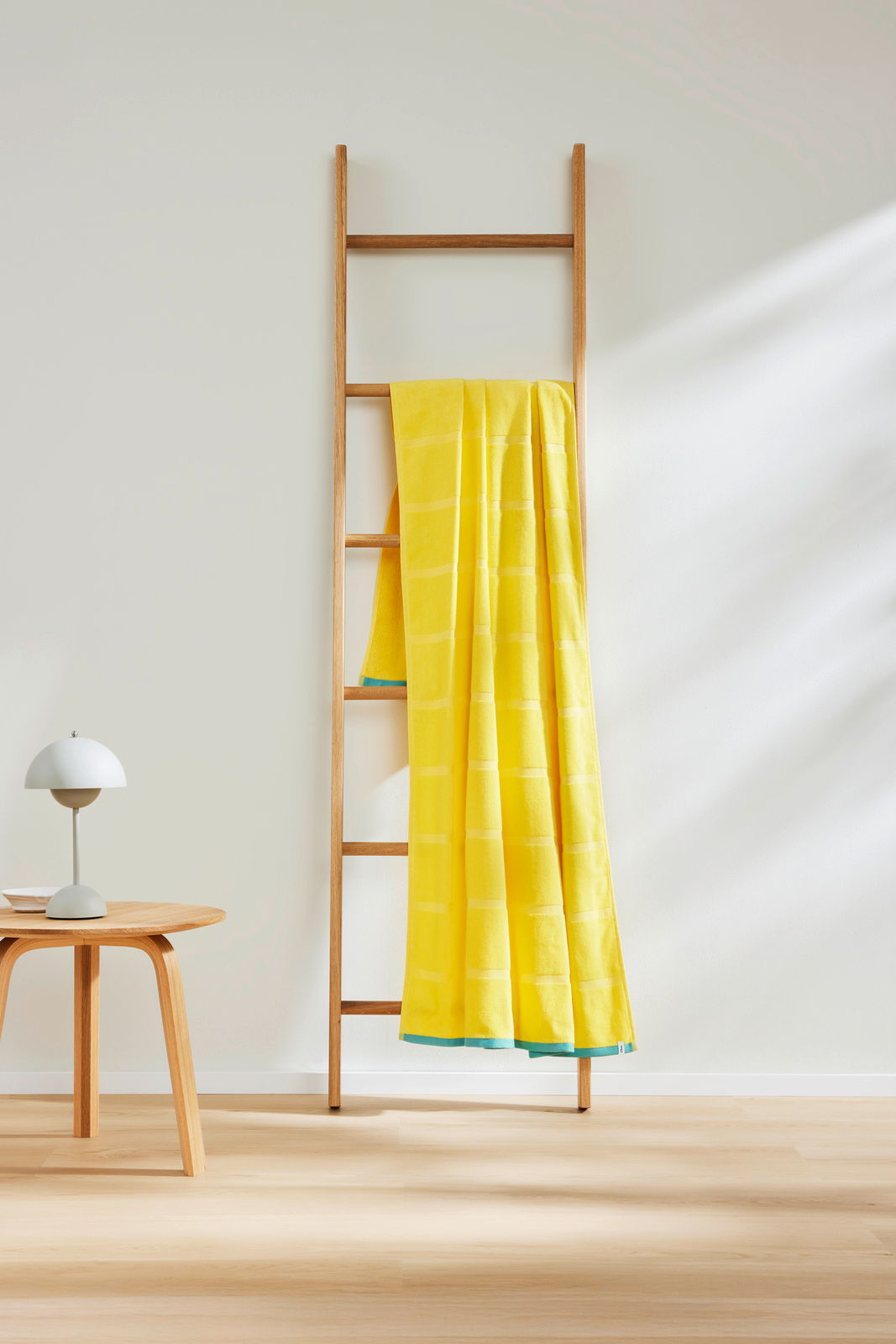 Gelbes Strandtuch 90x180cm auf einer Holzleiter, seitliche Perspektive