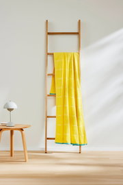 Gelbes Strandtuch 90x180cm auf einer Holzleiter, seitliche Perspektive