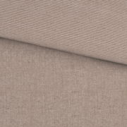 Nahaufnahme einer Wendebettwäsche mit gestreiftem und einfarbigem Design in neutralen Tönen.