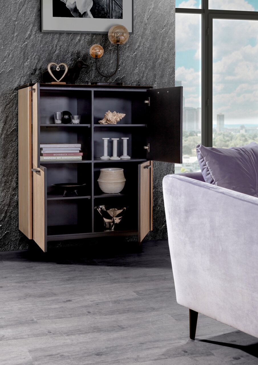 Modernes Highboard mit offenen Türen, das stilvoll dekoriert ist. Perspektive von vorne mit Blick auf die Inneneinrichtung und ein Fenster im Hintergrund.