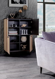 Modernes Highboard mit offenen Türen, das stilvoll dekoriert ist. Perspektive von vorne mit Blick auf die Inneneinrichtung und ein Fenster im Hintergrund.