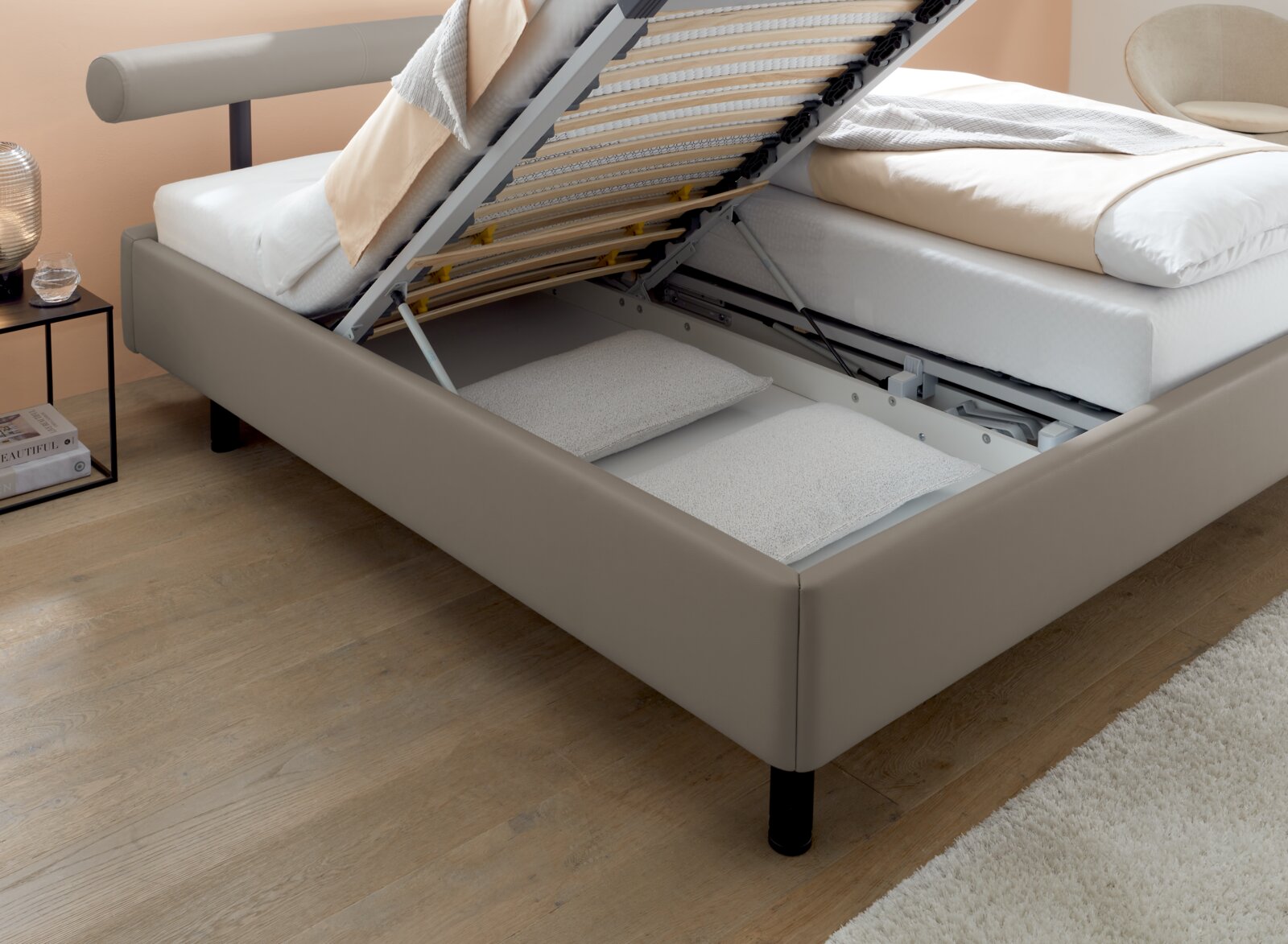 Polsterbett mit hochgeklappter Matratze und sichtbarem Stauraum, seitliche Perspektive