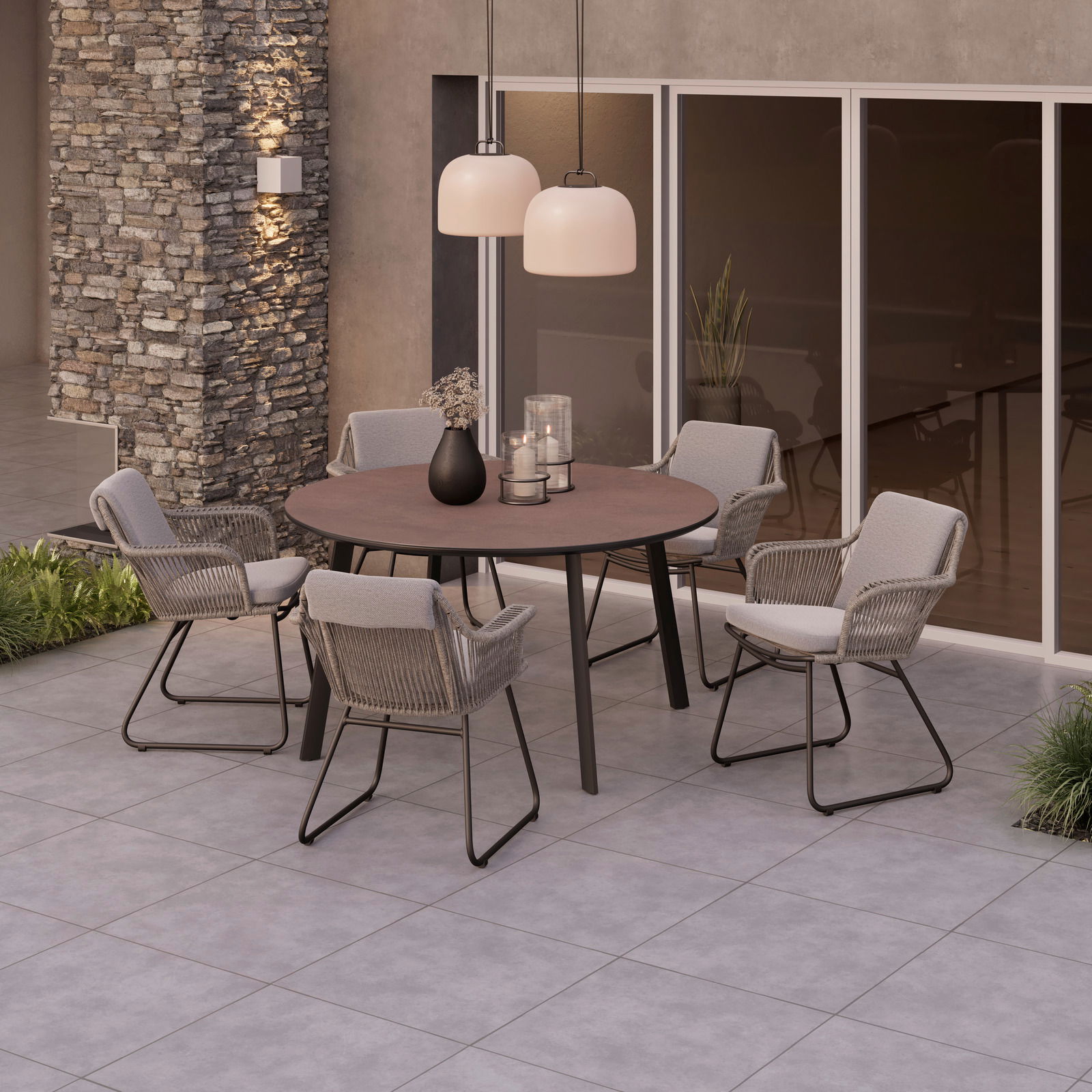 Runder Gartentisch mit vier Stühlen auf einer Terrasse, umgeben von moderner Architektur und Pflanzen, aus der Vogelperspektive.