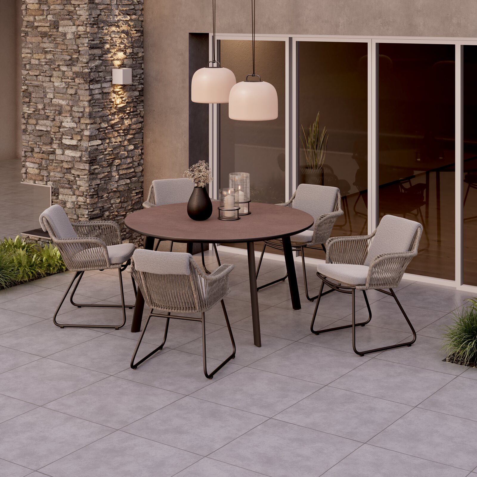 Runder Gartentisch mit vier Stühlen auf einer Terrasse, umgeben von moderner Architektur und Pflanzen, aus der Vogelperspektive.