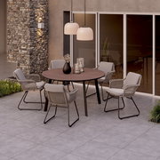 Runder Gartentisch mit vier Stühlen auf einer Terrasse, umgeben von moderner Architektur und Pflanzen, aus der Vogelperspektive.