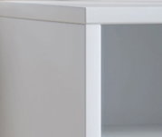 Detailansicht aus leichter Seitenperspektive auf die obere Ecke eines modernen weißen Möbelstücks mit klaren Linien und grauer Front