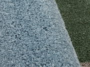 Nahaufnahme eines blauen Uni-Teppichs mit weicher, flauschiger Textur, von der Seite betrachtet.