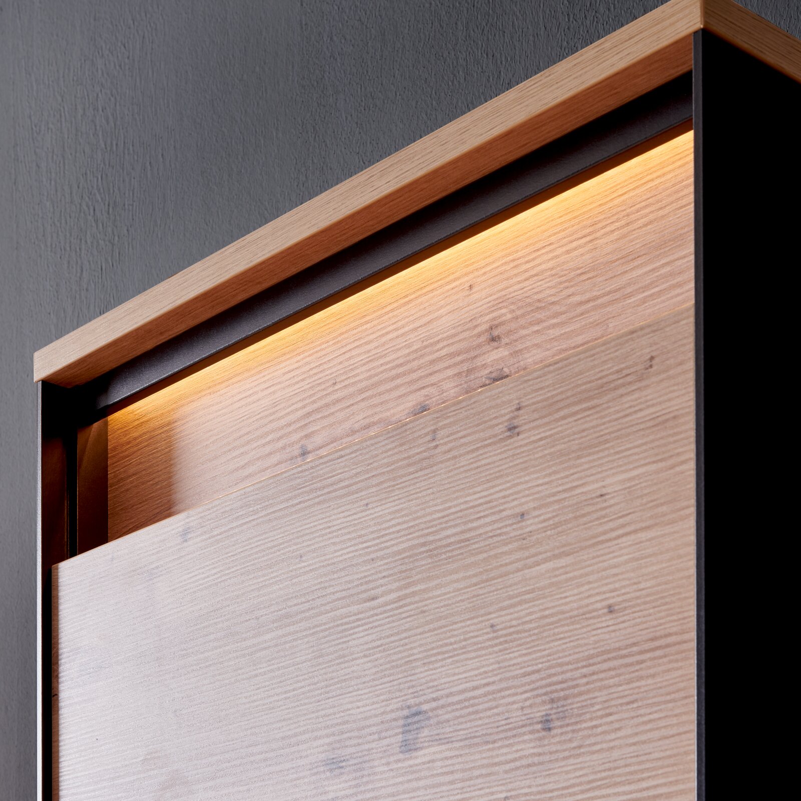 Detailweergave van een garderobekast met houten bekleding en ingebouwde verlichting van bovenaf.