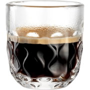 Nahaufnahme eines Espresso in einem strukturierten Glas mit Wellenmuster, seitliche Perspektive.