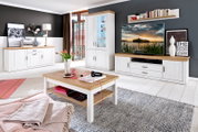 Helles Wohnzimmer-Set im Landhausstil mit weißer Holzoptik und Eichefarben-Absetzungen: Sideboard links, hohe Vitrine mittig, TV-Lowboard rechts und Couchtisch im Vordergrund; Perspektive: frontale Weitwinkelansicht leicht von links.