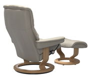 Rückansicht eines beigen Stressless Einzelsessels mit passendem Hocker, beide mit Holzgestell.