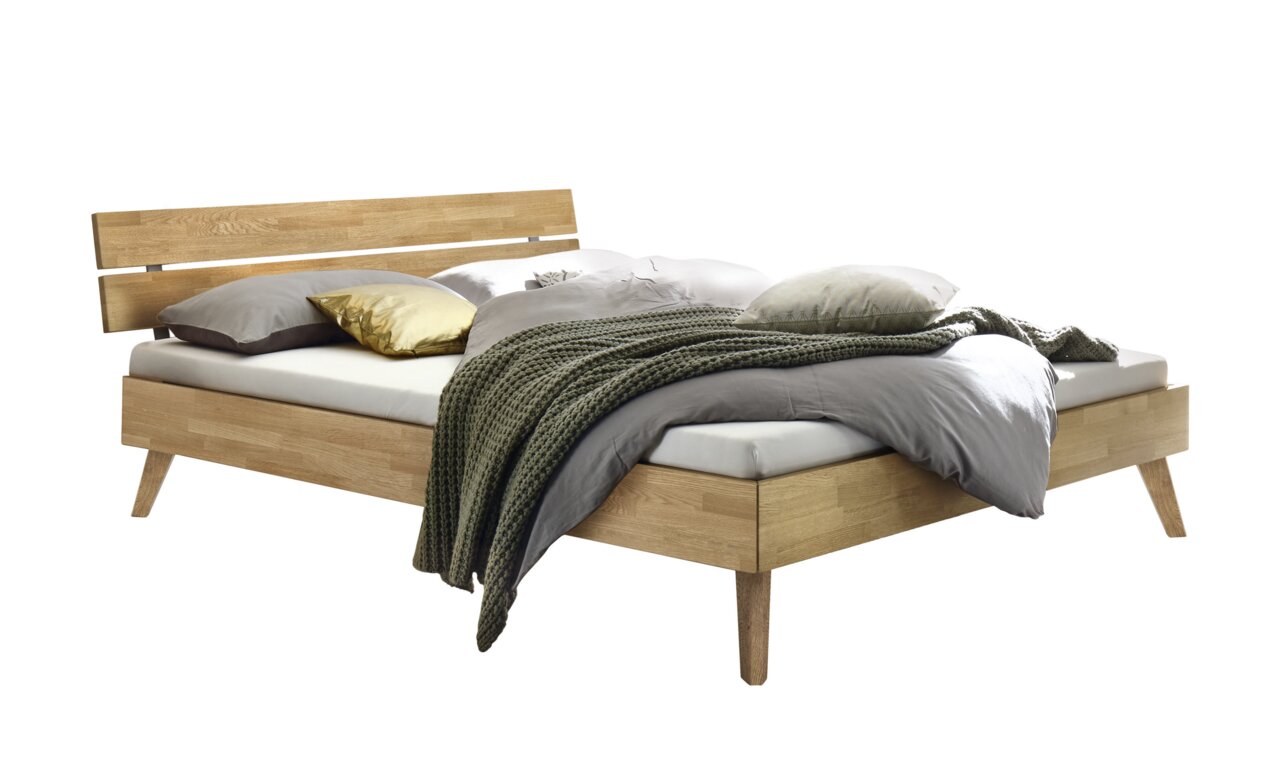Holzbett mit modernem Kopfteil aus Holz und Metall, seitliche Perspektive, dekoriert mit Kissen und Decke