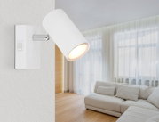 Moderne witte wandspot met schakelaar, gemonteerd in een lichte woonkamer, zijaanzicht.