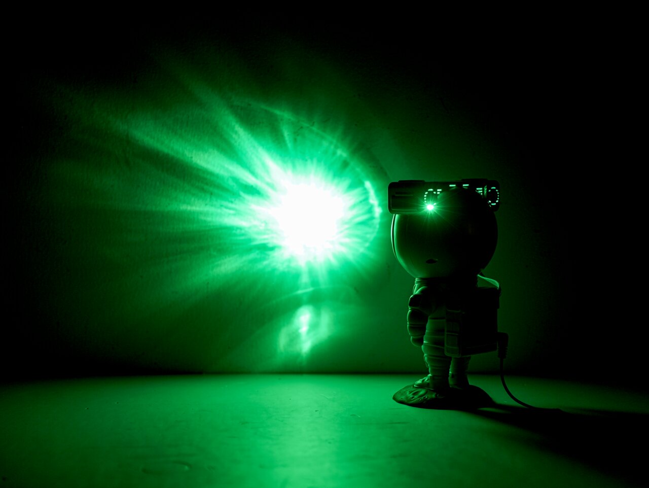 LED-Dekoleuchte in Form eines Astronauten, der mit einem grünen Lichtstrahl an die Wand projiziert. Seitliche Perspektive.