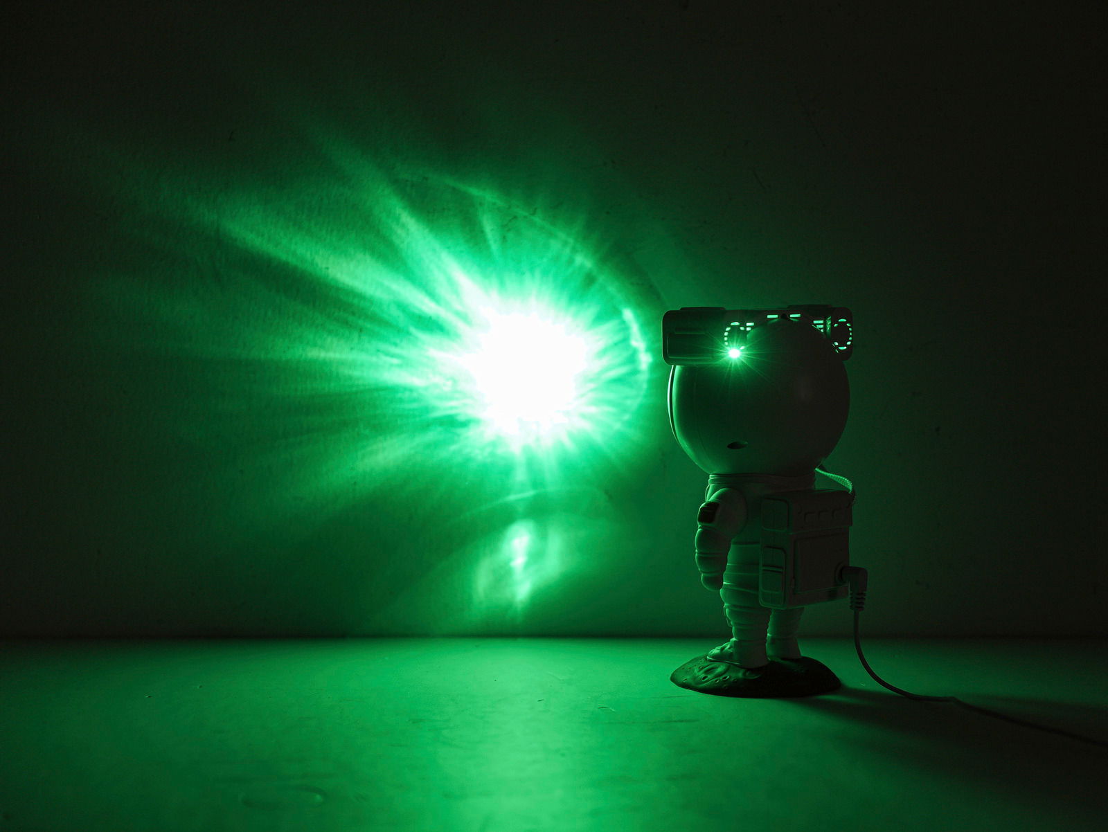 LED-Dekoleuchte in Form eines Astronauten, der mit einem grünen Lichtstrahl an die Wand projiziert. Seitliche Perspektive.