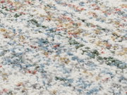 Nahaufnahme eines bunten Frisé-Teppichs mit weißen, blauen, grünen und roten Farbtönen, aus seitlicher Perspektive aufgenommen.