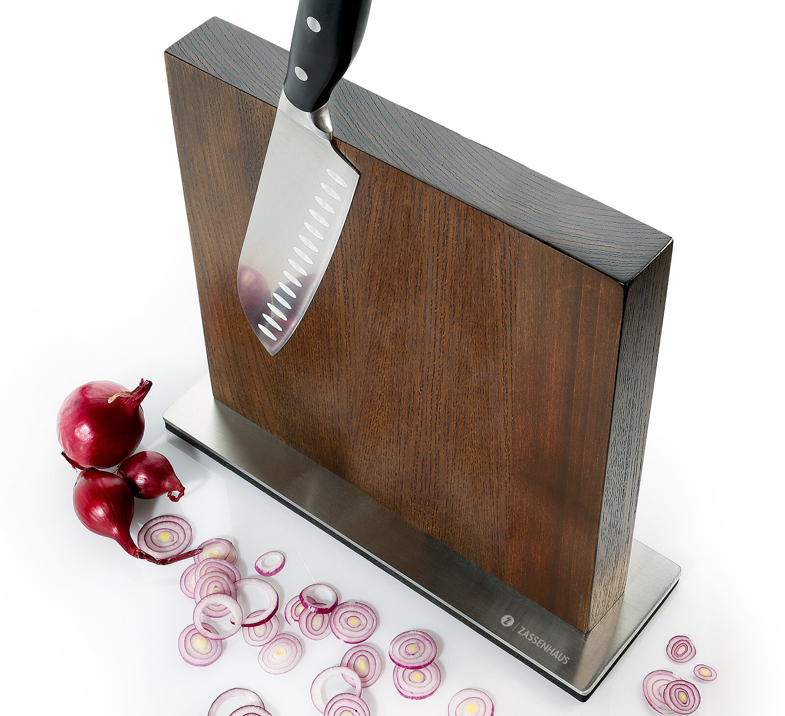 Magnet-Messerblock aus Esche mit einem Messer, das daran haftet, und geschnittenen roten Zwiebeln auf einer weißen Oberfläche, seitliche Perspektive.