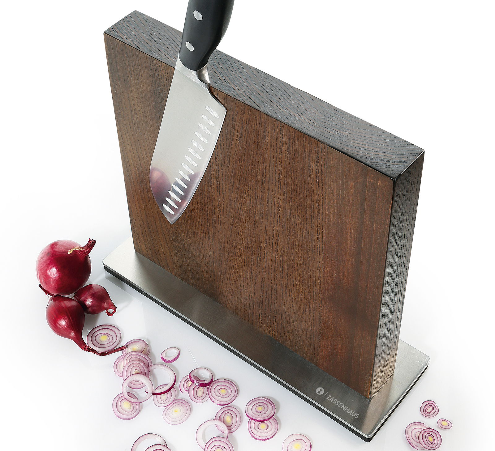 Magnet-Messerblock aus Esche mit einem Messer, das daran haftet, und geschnittenen roten Zwiebeln auf einer weißen Oberfläche, seitliche Perspektive.