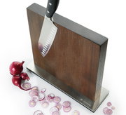 Magnet-Messerblock aus Esche mit einem Messer, das daran haftet, und geschnittenen roten Zwiebeln auf einer weißen Oberfläche, seitliche Perspektive.