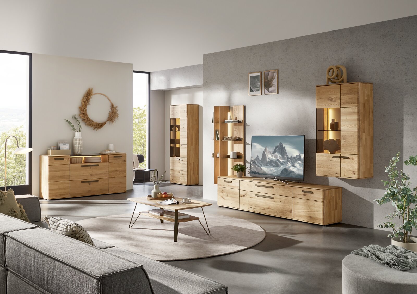 Modernes Wohnzimmer mit heller Massivholz-Wohnwand (Lowboard mit TV, Wandvitrine und Regal) sowie Sideboard und Hochschrank, Frontansicht in leichter Weitwinkelperspektive von links.