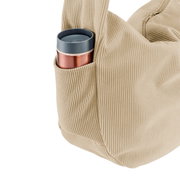 Beige Cord-Tragetasche mit Reißverschluss und Außentasche, darin ein Thermobecher; Detailansicht aus seitlicher Perspektive