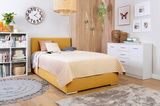 Gemütliches Schlafzimmer mit einem Boxbett in Senfgelb, umgeben von moderner Dekoration und Möbeln, aus einer seitlichen Perspektive fotografiert.