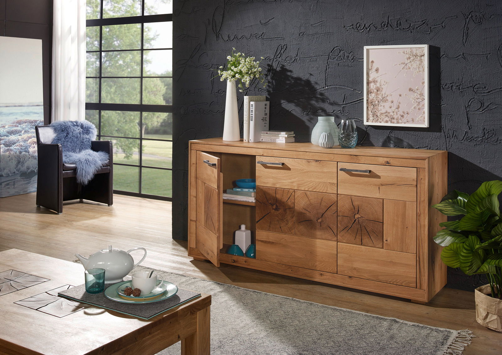 Holzsideboard MERAN in einem modernen Wohnzimmer, frontal fotografiert, mit dekorativen Elementen wie Vasen und Büchern darauf.