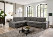 Graues, modernes U-förmiges Wohnlandschaft-Ecksofa mit breiter Ottomane und gepolsterter Rückenlehne in hellem Wohnzimmer; Perspektive: frontale leicht schräge Ansicht von links.