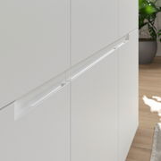 Nahaufnahme eines weißen Sideboards mit modernen, integrierten Griffen, seitliche Perspektive