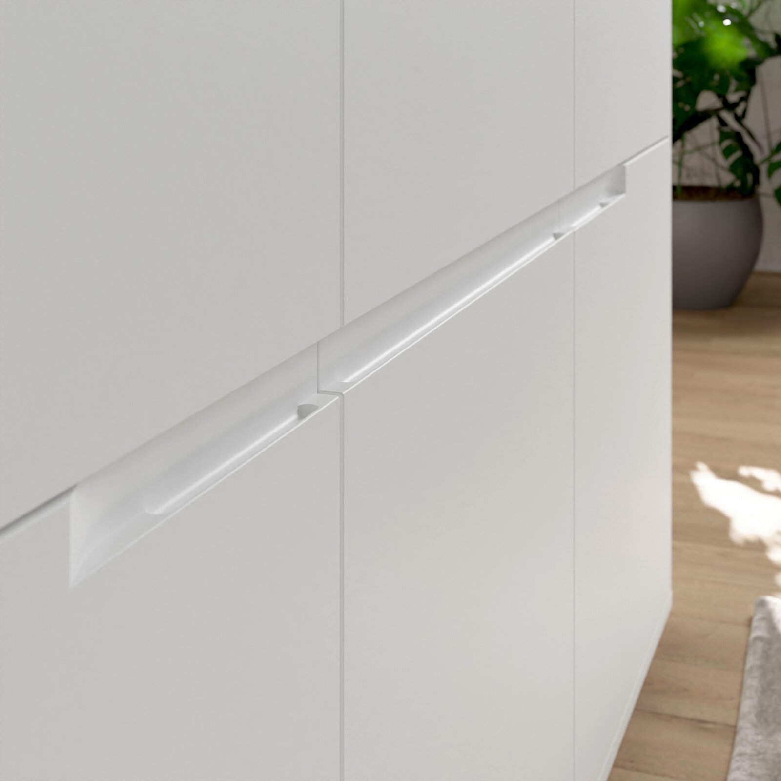 Nahaufnahme eines weißen Sideboards mit modernen, integrierten Griffen, seitliche Perspektive