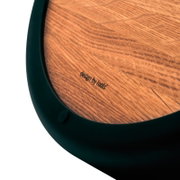 Detailaufnahme aus schräger Perspektive: runde Holzoberfläche mit Maserung und eingeprägtem Schriftzug „design by tools“ in einem schwarzen Metallrahmen