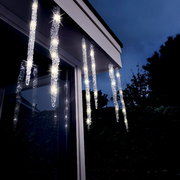 LED-Eiszapfenlichter mit Blitz-Effekt, aufgehängt an einer Dachkante bei Dämmerung, von unten betrachtet.