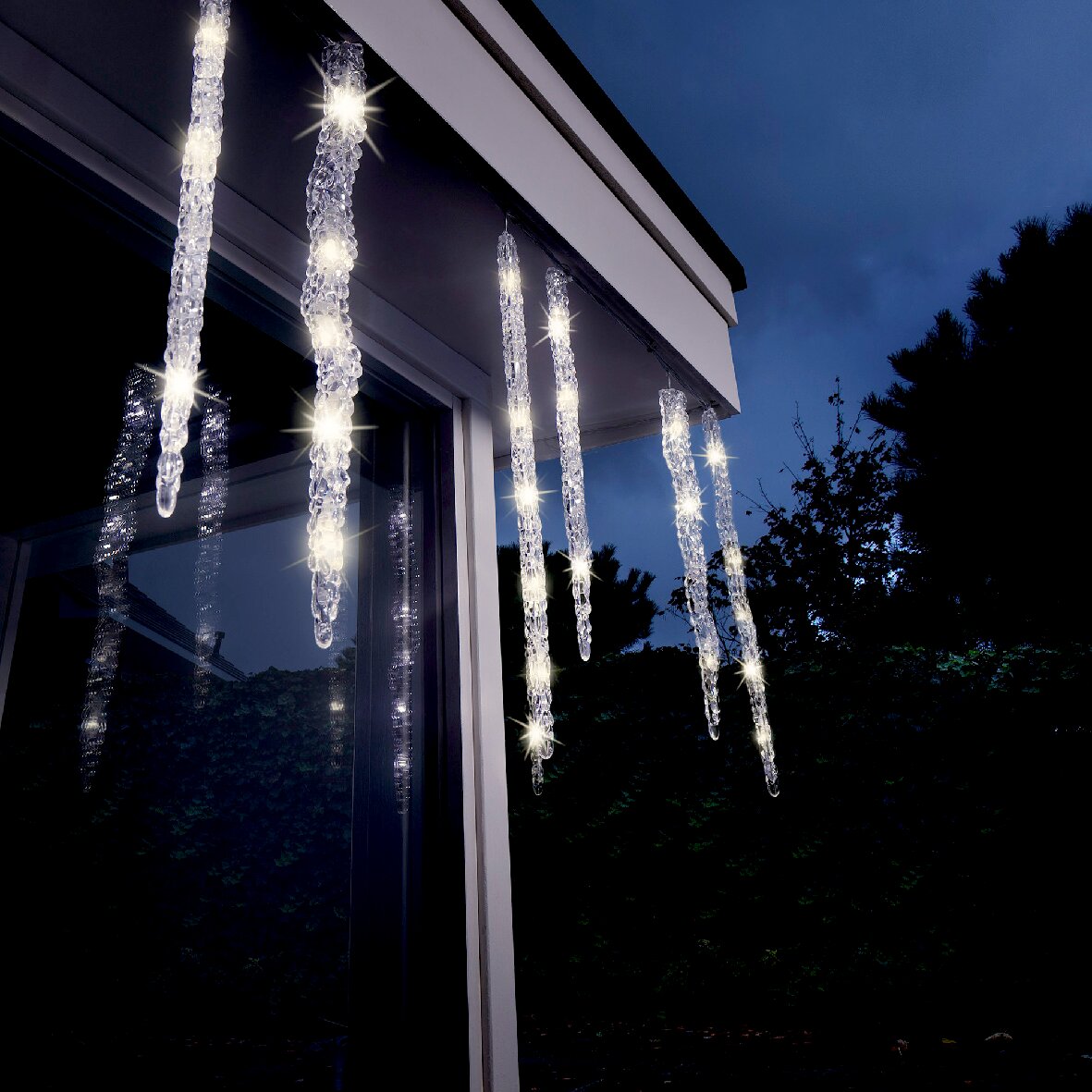 LED-ijspegellampjes met knipperend effect, opgehangen aan een dakrand bij schemering, van onderaf gezien.