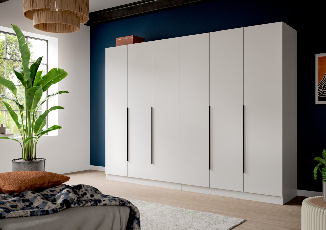 Großer weißer Kleiderschrank mit sechs Türen und langen schwarzen Griffen in modernem Schlafzimmer vor dunkelblauer Wand, Perspektive: frontale Ansicht leicht von links.