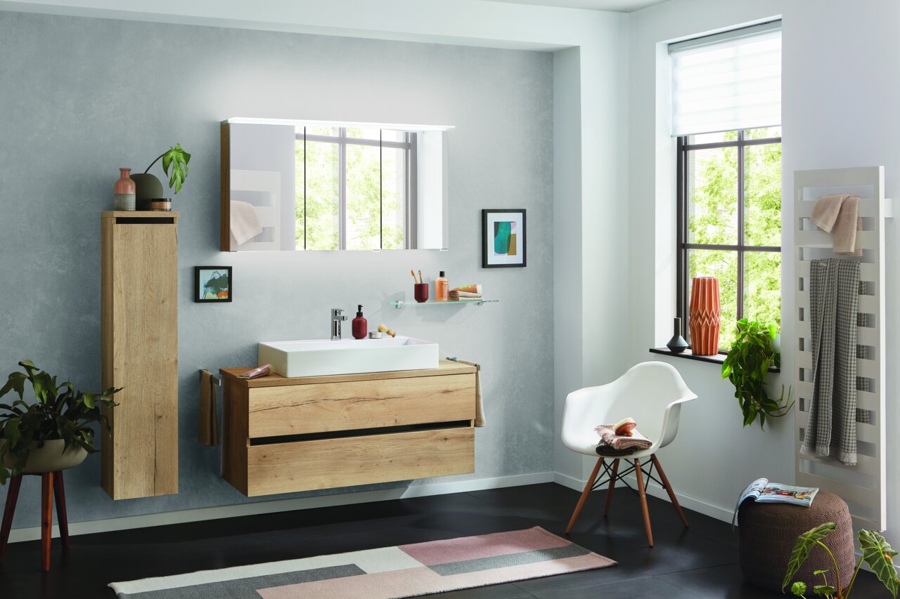 Dieter Knoll Badkombination PONTE Moderne Badkombination mit Holzoptik, bestehend aus einem Waschtisch mit Unterschrank, einem hohen Schrank und einem beleuchteten Spiegel, seitliche Perspektive.