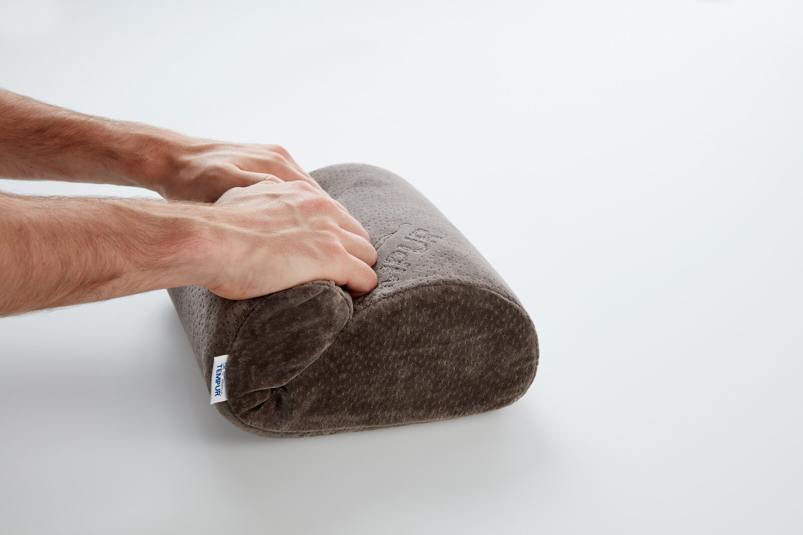 Tempur Reisekissen in Nahaufnahme, seitliche Perspektive, mit Händen, die das Kissen zusammendrücken.