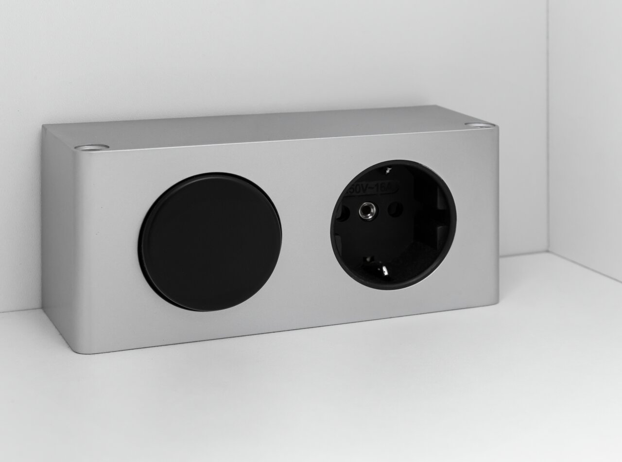 Silberne Steckdose mit einer schwarzen Abdeckung, seitliche Perspektive