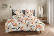 Blumige Bettwäsche mit Aquarell-Blütenmuster in Orange, Rosa und Grün auf weißem Grund, auf einem grauen Bett im Schlafzimmer – Frontansicht leicht von oben.
