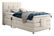 Boxspringbed in zijaanzicht met een beige stoffen bekleding, hoofdeinde, blauwe deken en kussens.
