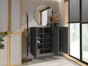 Moderner Hängeschuhschrank in dunkler Farbe mit offenen Türen, gefüllt mit Schuhen, in einem stilvoll eingerichteten Raum mit rundem Spiegel und Fenster im Hintergrund, seitliche Perspektive.