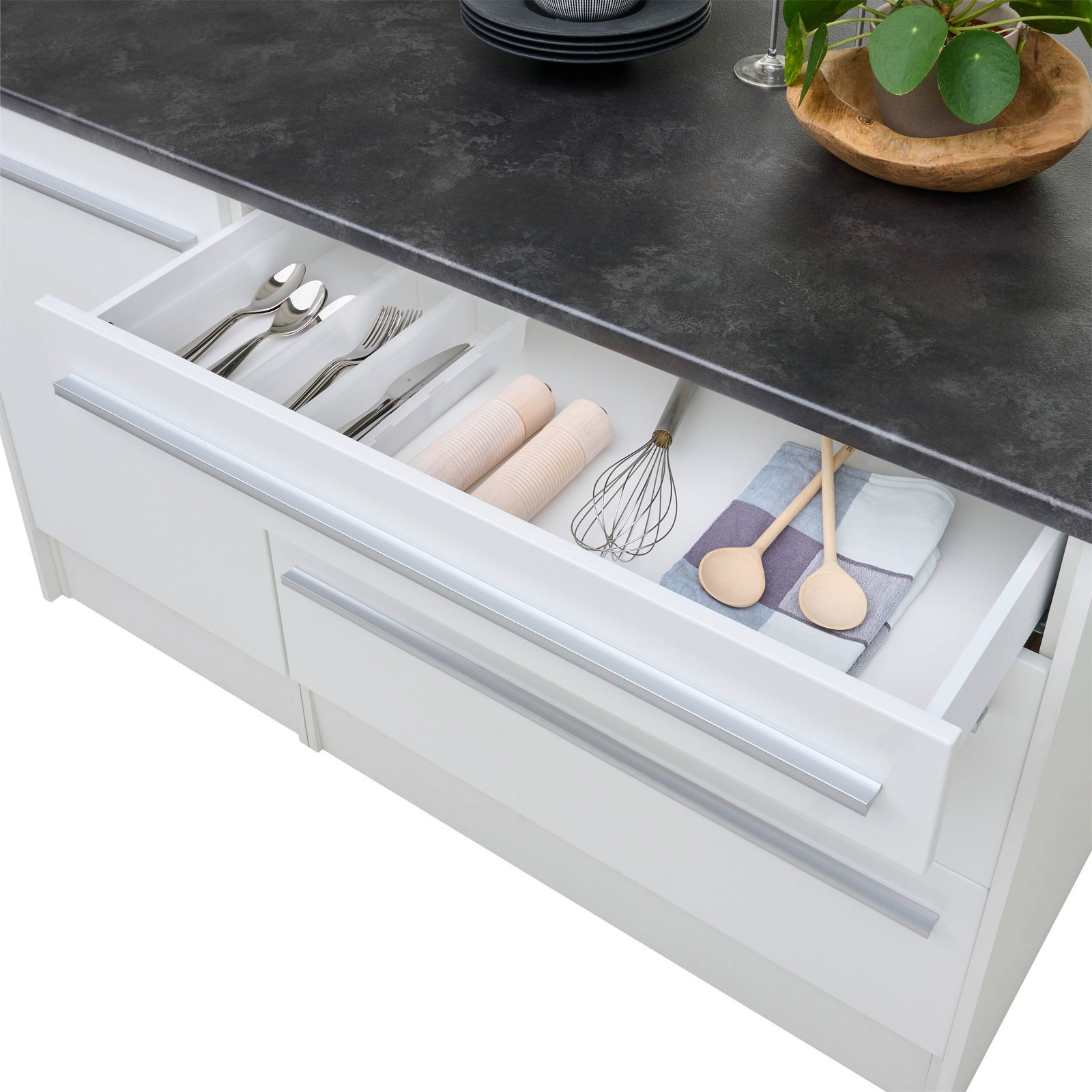 Kücheninsel mit geöffneter Schublade, die Besteck, Küchenutensilien und Handtücher zeigt, aus der Vogelperspektive.