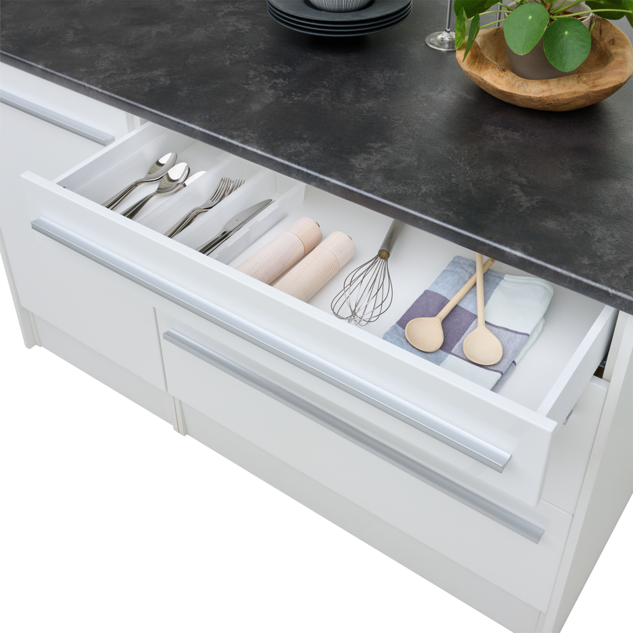 Kücheninsel mit geöffneter Schublade, die Besteck, Küchenutensilien und Handtücher zeigt, aus der Vogelperspektive.