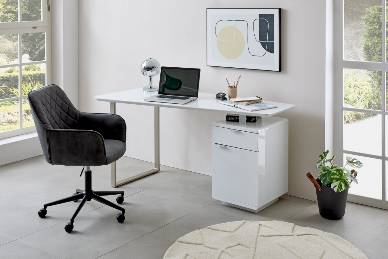 Moderner Schreibtisch in einem hellen Raum mit einem schwarzen Bürostuhl, einem Laptop und Dekorationen, seitliche Perspektive.