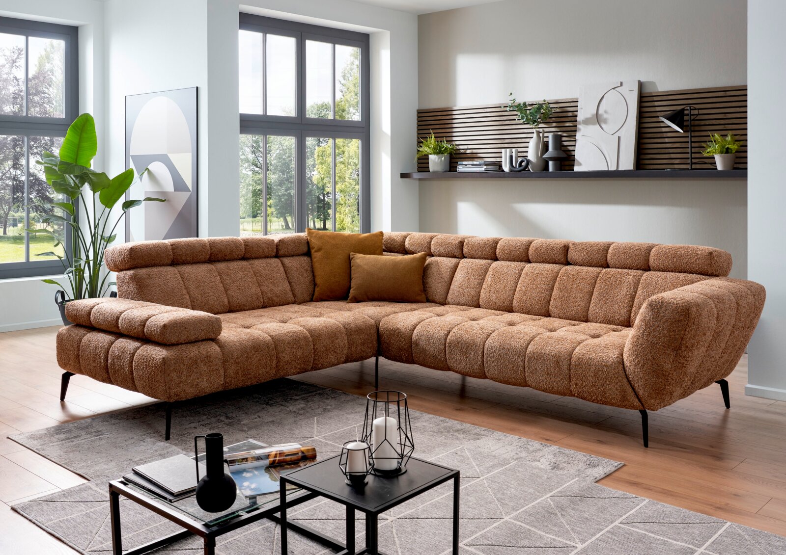Bruin bouclé hoekbank in moderne woonkamer, driekwart aanzicht van voren met chaise longue links, zwarte poten en sierkussens