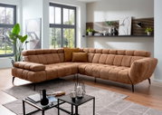 Bruin bouclé hoekbank in moderne woonkamer, driekwart aanzicht van voren met chaise longue links, zwarte poten en sierkussens