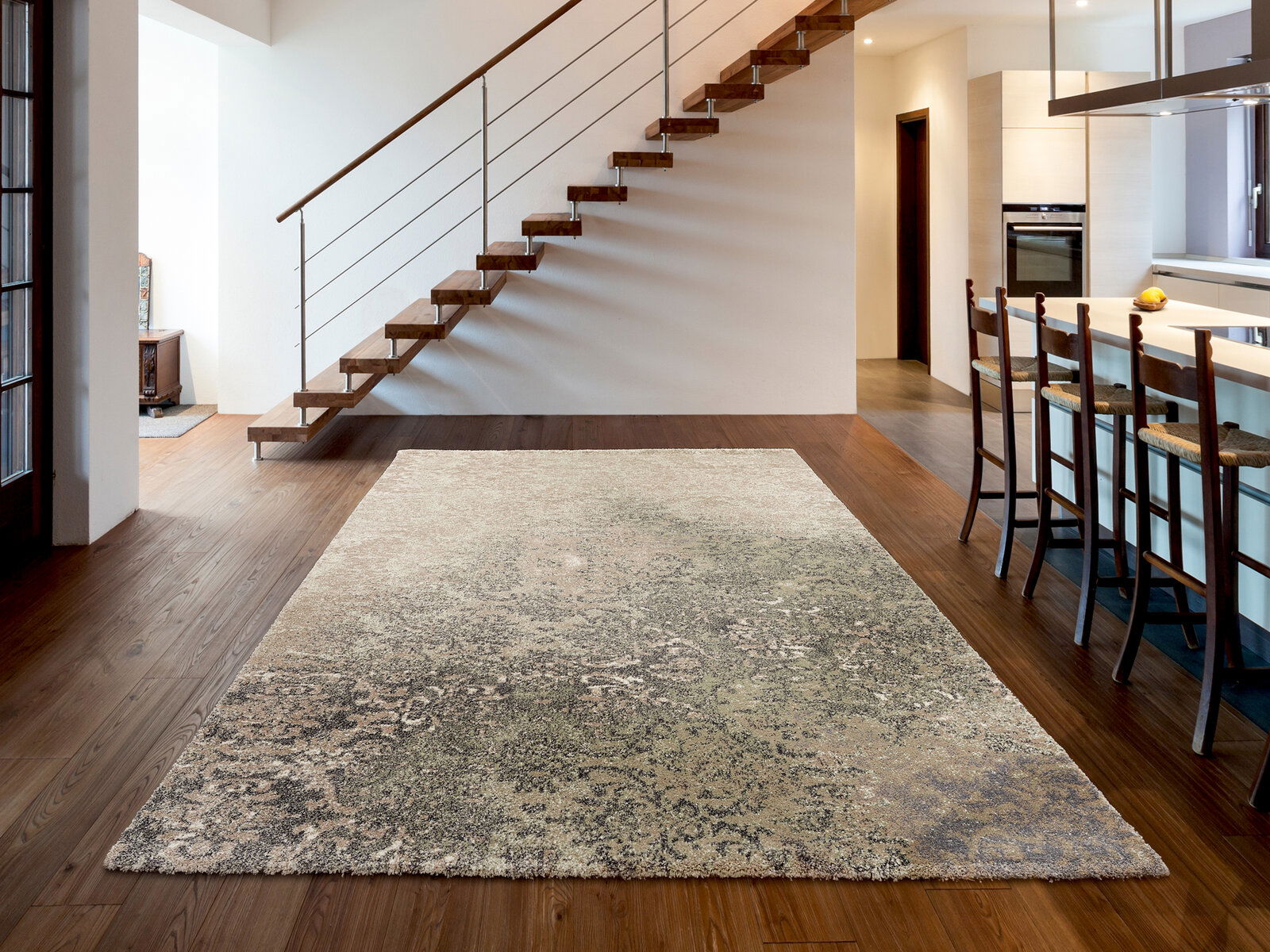 Designer Teppich in modernem Wohnzimmer mit Holztreppe und Küchenbereich, Perspektive von vorne